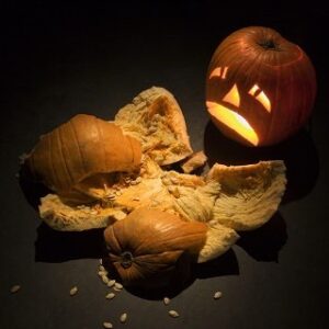 Upset jack-o'-lantern looking at smashed pumpkin.